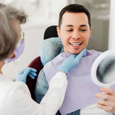 Man smiling at reflection in mirror with dentist